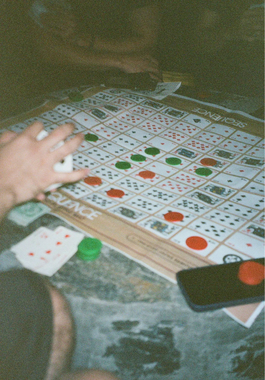 Close-up of a board game involving playing cards and green and red chips on a game mat labeled 'SCIENCE'.